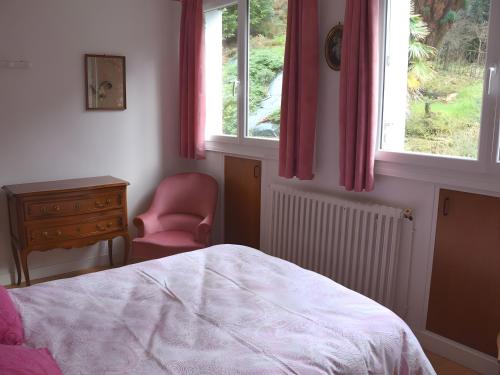 a bedroom with a bed and a chair and windows at Maison Gwel Kaer in Perros-Guirec