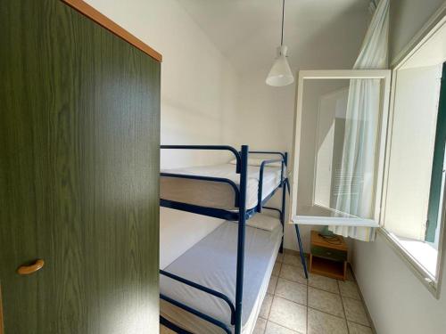 a small room with two bunk beds and a window at Ville Verdi - private garden in Bibione