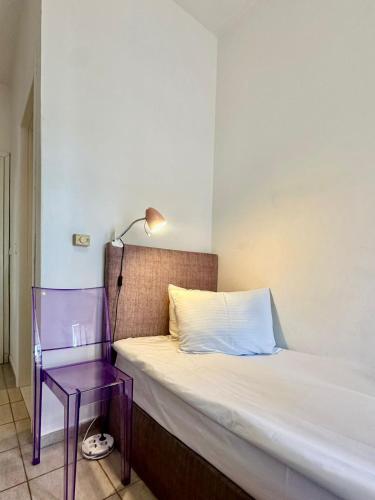 a bed and a purple chair in a room at Petit City in Orestiada