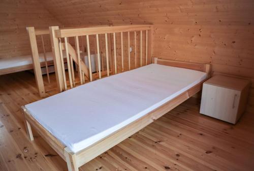 a bed in a wooden room with a wooden floor at Ośrodek Rekreacyjno-Wypoczynkowy Żuczek, Debrzno in Debrzno