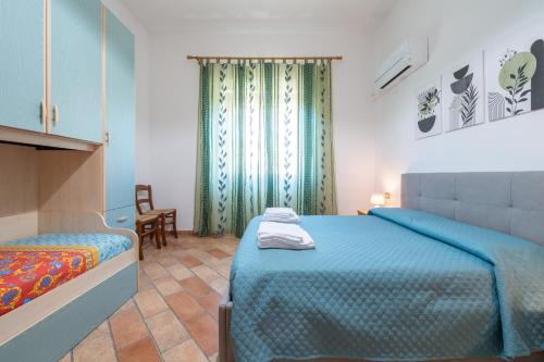a bedroom with a bed and a chair and a window at Su Suergiu in San Giovanni Suergiu