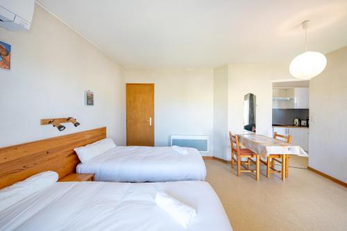 a hotel room with two beds and a dining table at Les Mimosas - Appartement 09 in Cazaubon