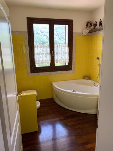 a yellow bathroom with a tub and a window at Casa di Eli e Matte in Le Serucce