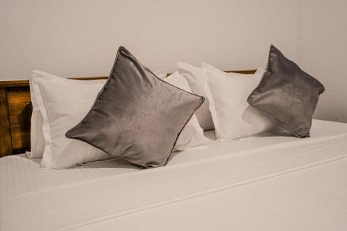 a bed with white pillows and grey pillows at Villa R in Negombo