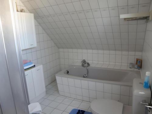 a white bathroom with a tub and a toilet at Haus Peeneblick in Freest