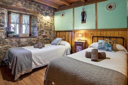 a bedroom with two beds and a stone wall at Casa Rural Cornatel in Villavieja