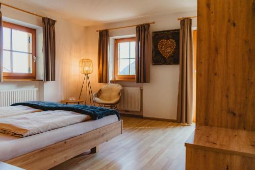 a bedroom with a bed and a chair and windows at Apartment Andreas - Gallhof in Vollan