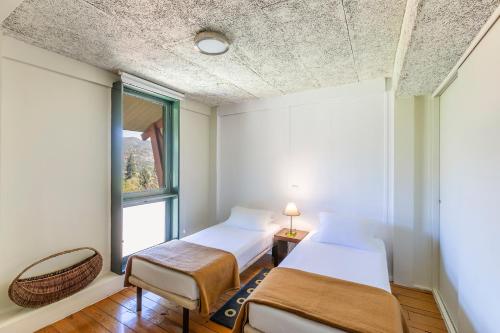 two beds in a room with a window at HI Geres - Pousada de Juventude do Gerês in Geres