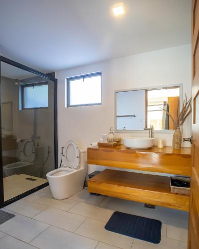 a bathroom with a sink and a toilet and a tub at Villa Kalachuchi Bohol in Panglao Island