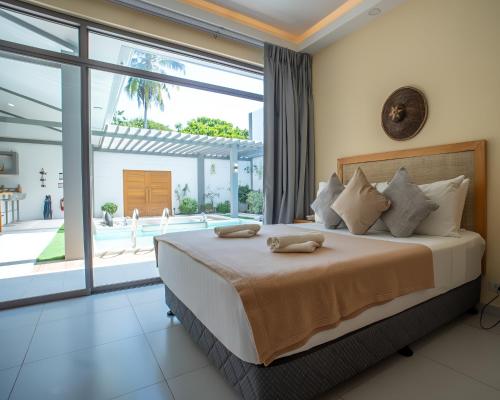 a bedroom with a large bed and a large window at Villa Kalachuchi Bohol in Panglao Island