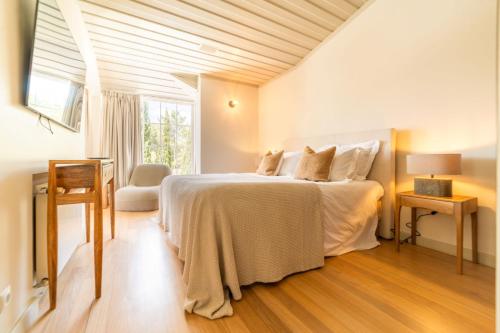 a white bedroom with a bed and a window at Villa Alegria in Azeitao