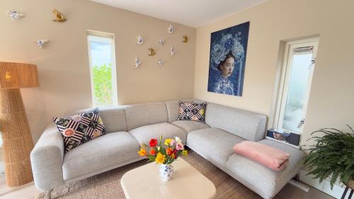 a living room with a couch and a table with flowers at Tulipa Near Beach & Dunes with Free Parking in Noordwijkerhout