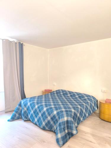 a bed with a blue plaid blanket in a room at Levico Antiche Terme Apartment in Levico Terme