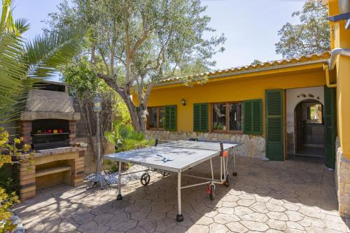a ping pong table in front of a yellow house at Villa El Mal Pas / Can Seguinet in Alcudia