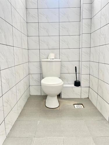 a bathroom with a toilet in a white tiled wall at Auryhomes in Mombasa