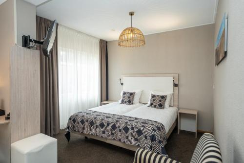 a hotel room with a bed and a chandelier at Hotel Zeerust in De Koog