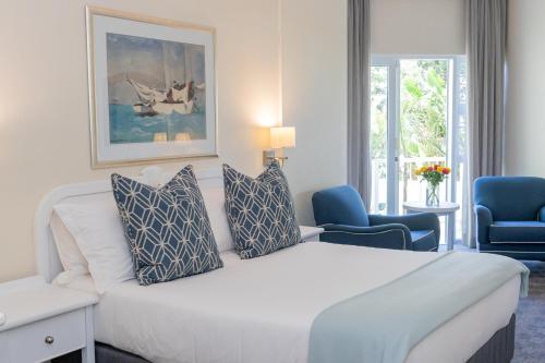 ein Hotelzimmer mit einem großen weißen Bett und blauen Stühlen in der Unterkunft The Beach Hotel in Port Elizabeth