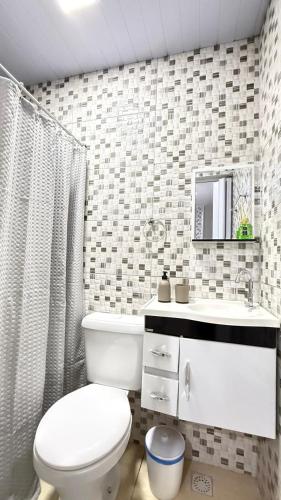 a bathroom with a white toilet and a sink at Casa no Vidigal da Nilda in Rio de Janeiro