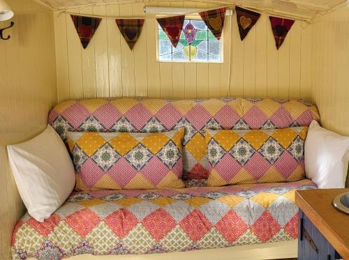 a couch in a room with colorful pillows on it at Firbank Park Shepherd Huts in Dinnet