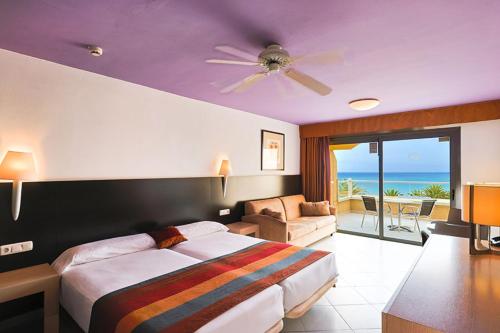 a bedroom with a bed and a living room with the ocean at SBH Monica Beach Resort in Costa Calma