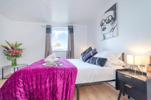a bedroom with a bed with a pink blanket on it at Stylish 2-Bed Manning Gardens in South Norwood