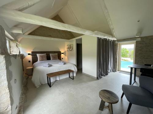 a bedroom with a bed and a table in a room at Mas de Méjas Chambre d'hôtes La Pierraille in Calvignac