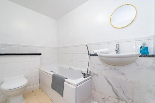 a white bathroom with a sink and a toilet at Stylish 2-Bed Manning Gardens in South Norwood