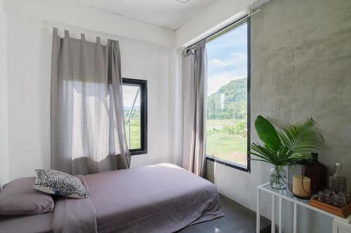 a bedroom with a bed and a large window at Shade House - Phuket Downtown in Phuket