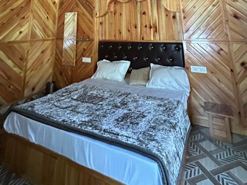 a bed in a room with a wooden wall at Maya Homestay & Cafe in Kasol