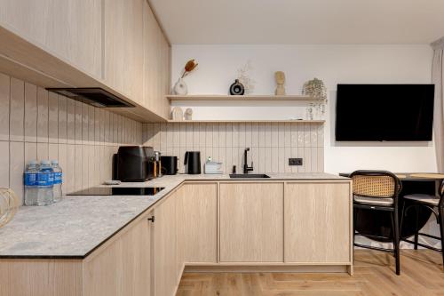 a kitchen with wooden cabinets and a tv in it at Sunny Hill in Palanga