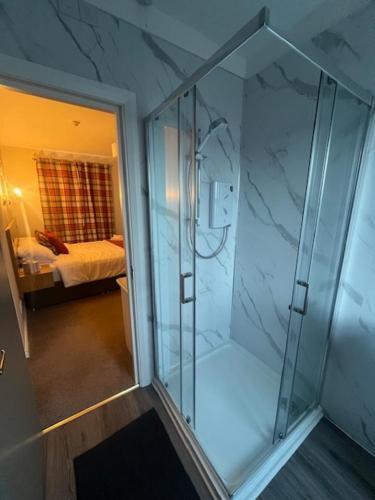 a glass shower in a room with a bedroom at Central Bar Guesthouse in Cushendall