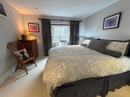 a bedroom with a bed and a chair and a window at Central Stow Bakehouse Flat in Stow on the Wold