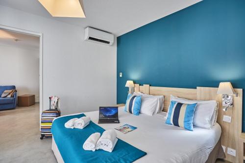 a hotel room with two beds with blue walls at Hôtel Nakara by Odalys in Cap d'Agde