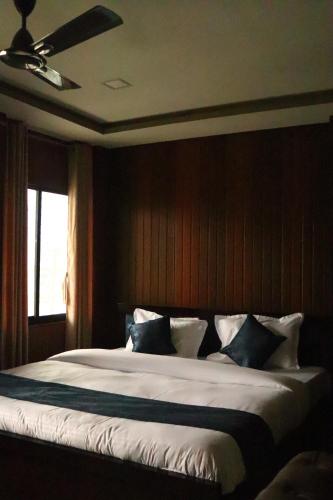 a bedroom with a large bed with a ceiling fan at Hotel Golden Mahseer in Tezu