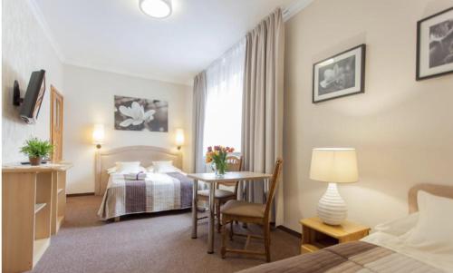 a hotel room with a bed and a desk and a table at Villa Anna - Noclegi Rooms - FREE parking, taras, 1500m do Starówki in Gdańsk