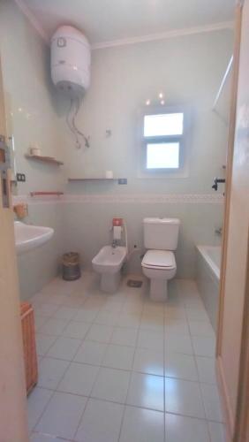 a white bathroom with a toilet and a sink at Hurghada Beach House in Hurghada