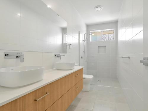 a white bathroom with two sinks and a toilet at Lillian Waters Retreat in Yamba