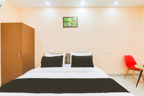 a bedroom with a large bed and a red chair at Hotel O Happy Times Vishveshwar Park in Gomti Nagar