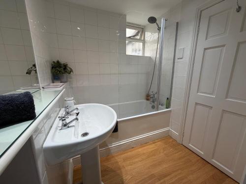 a white bathroom with a sink and a shower at Central Stow Bakehouse Flat in Stow on the Wold