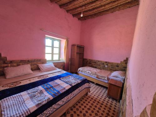 a bedroom with two beds and a window at Auberge camping la tradition in Merzouga
