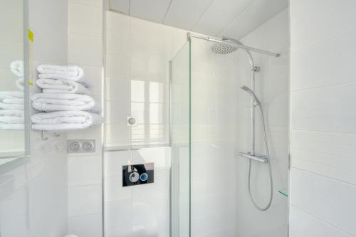 a white bathroom with a shower and towels at Hôtel de Bellevue Paris Gare du Nord in Paris
