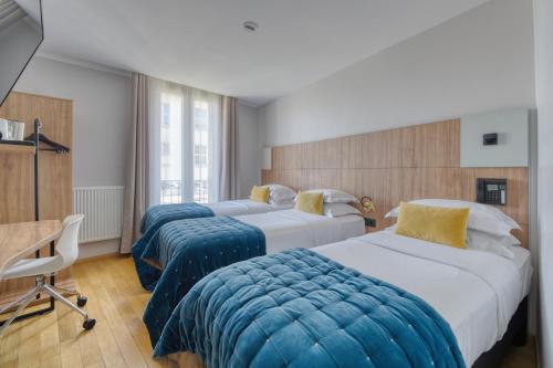 a hotel room with three beds and a desk at Hôtel de Bellevue Paris Gare du Nord in Paris