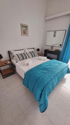 a bedroom with a large bed with a blue blanket at Glossy Messinian Escape - Cozy Yard Apartment in Filiatra