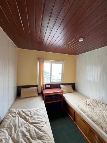 two beds in a small room with a window at Hotel Mountain View - Namche in Namche