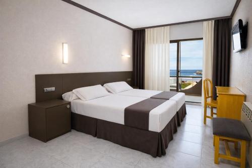 a hotel room with a bed and a desk and a window at Hotel las Dunas in Noja
