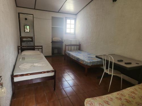 a room with two beds and a table and a chair at Solemar in Guarapari