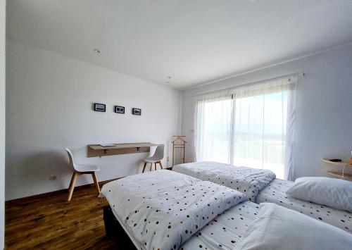 a bedroom with two beds and a desk and a window at Chambres d'hôtes La Ganivelle in Servant