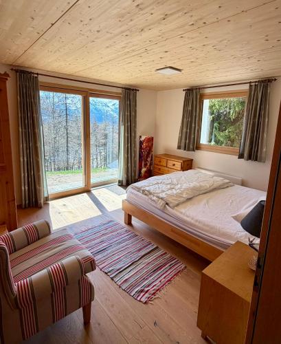 a bedroom with a bed and a couch and windows at Chalet Silentium in Bellwald