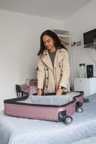 a woman is opening a suitcase on a bed at Bed and Breakfast Amsterdam Holy Dove in Amsterdam