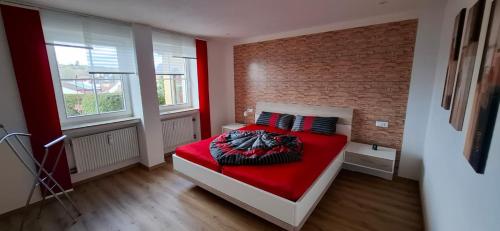 a bedroom with a red bed and a brick wall at Ferienwohnung zum Albuch in Nördlingen